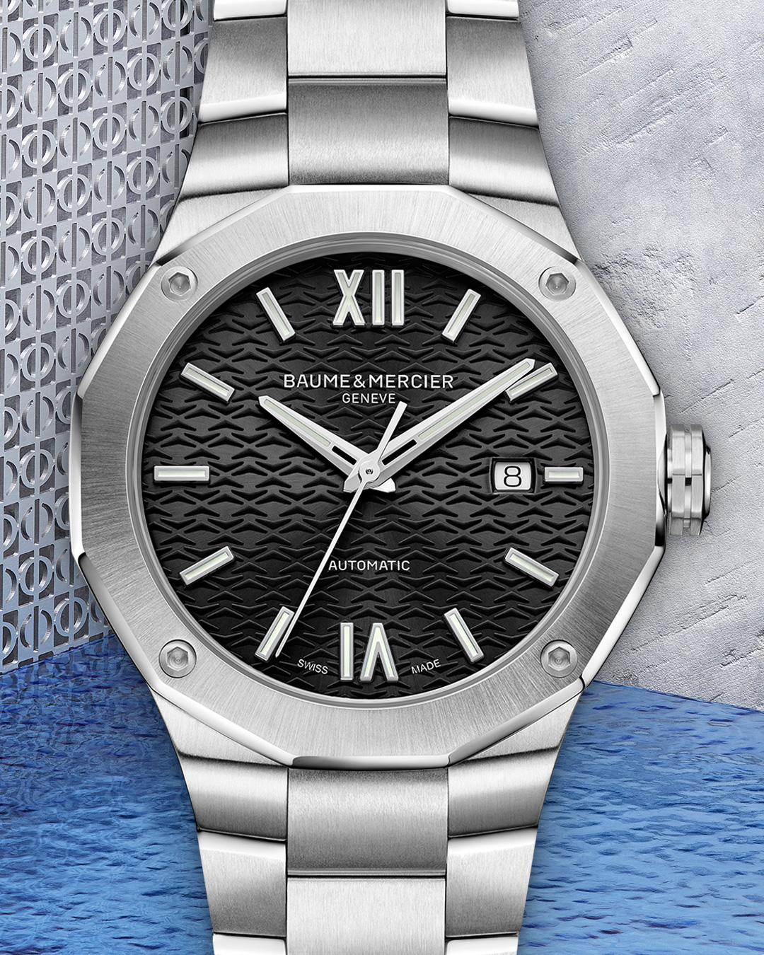 A silver Baume & Mercier watch with a black textured dial, silver hands, and a date window.