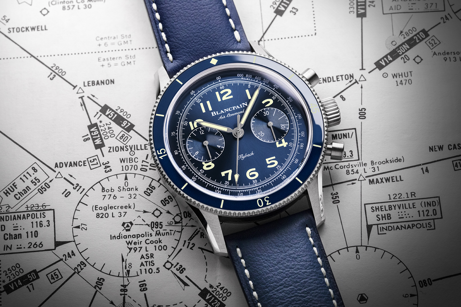 A close-up of a Blancpain Air Command Flyback chronograph watch with a blue dial, set against the backdrop of an aviation chart.