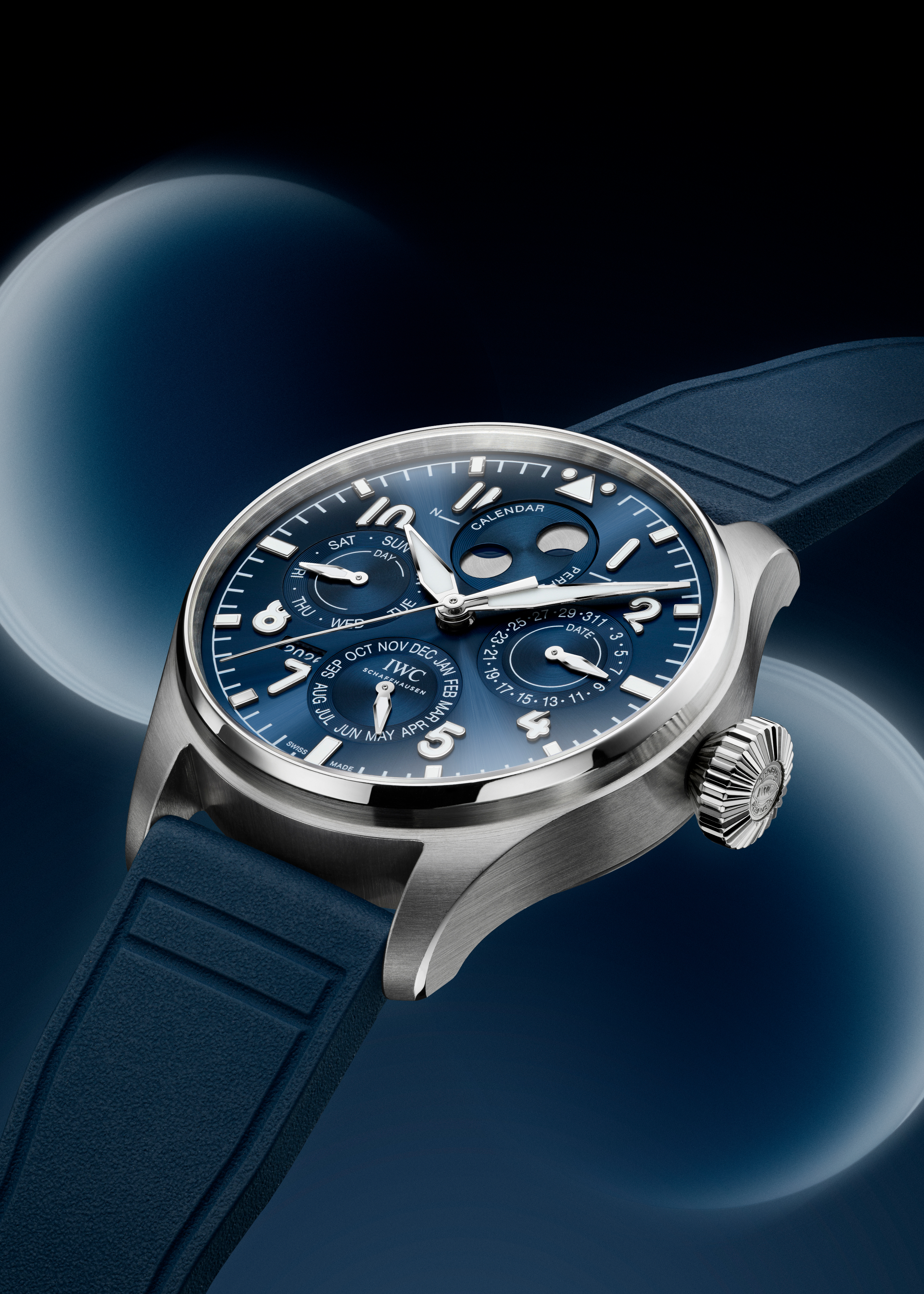 A silver IWC Schaffhausen watch with a blue face and blue rubber strap, displaying day, date, month, and year.