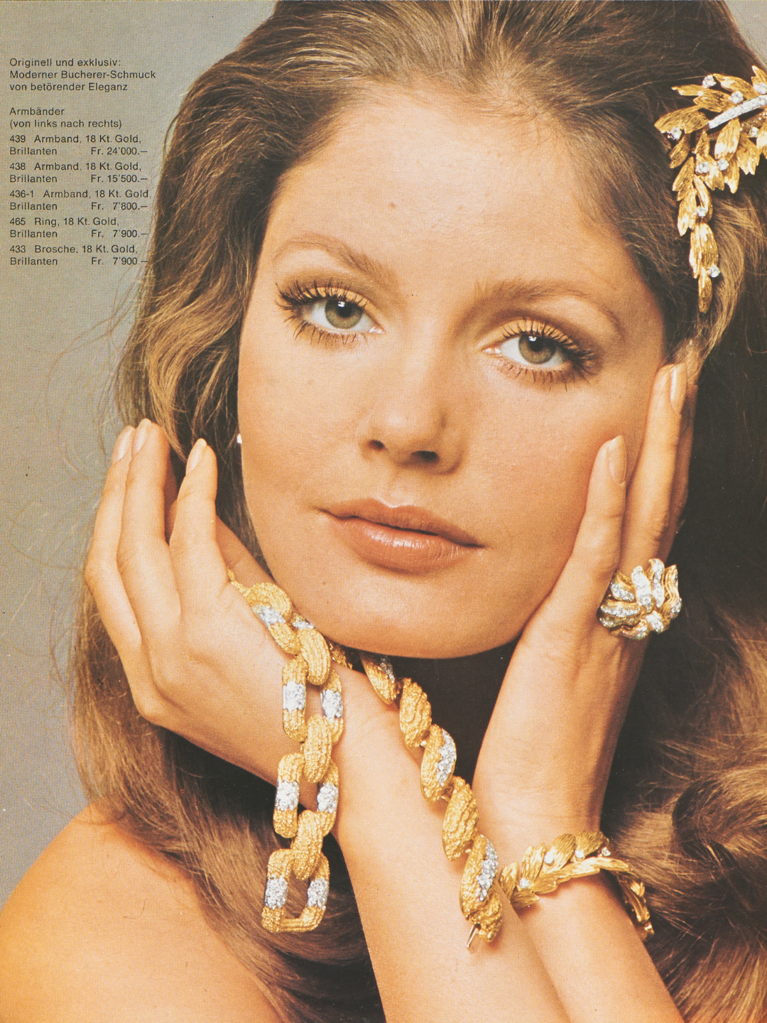A woman with long brown hair wearing a gold bracelet, ring, and hair ornament.