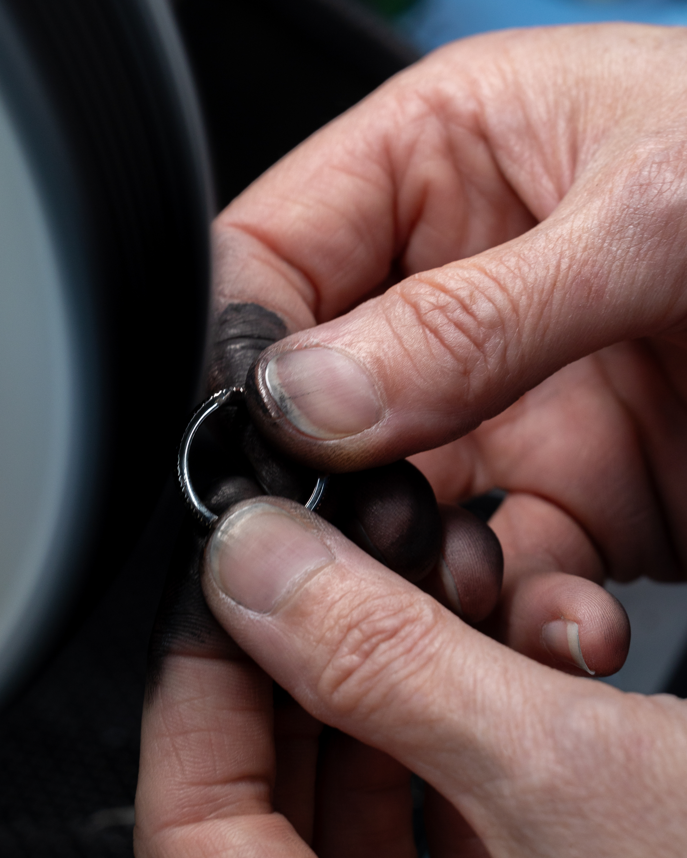 Hands with smudged fingers holding a silver ring.