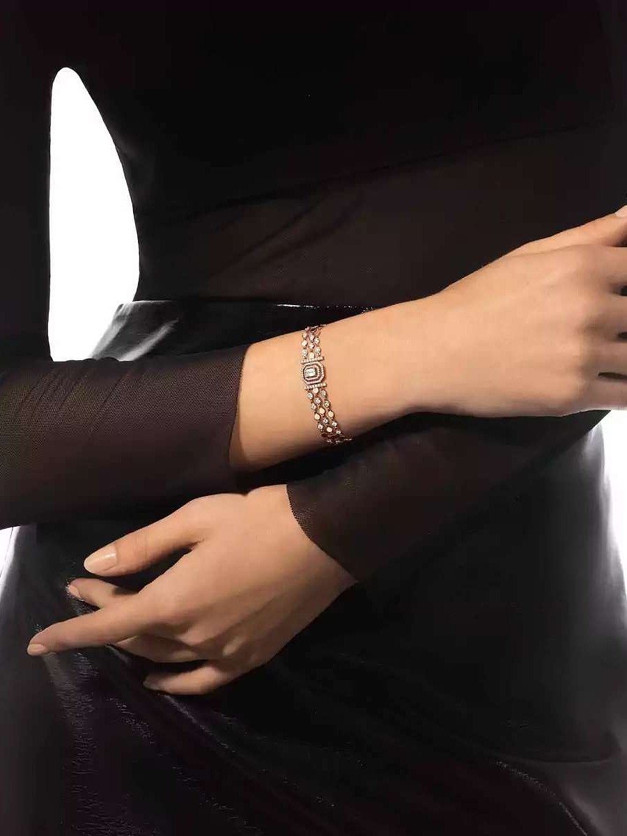 Gros plan sur une personne portant un bracelet multirangs en diamants et or rose à son poignet.