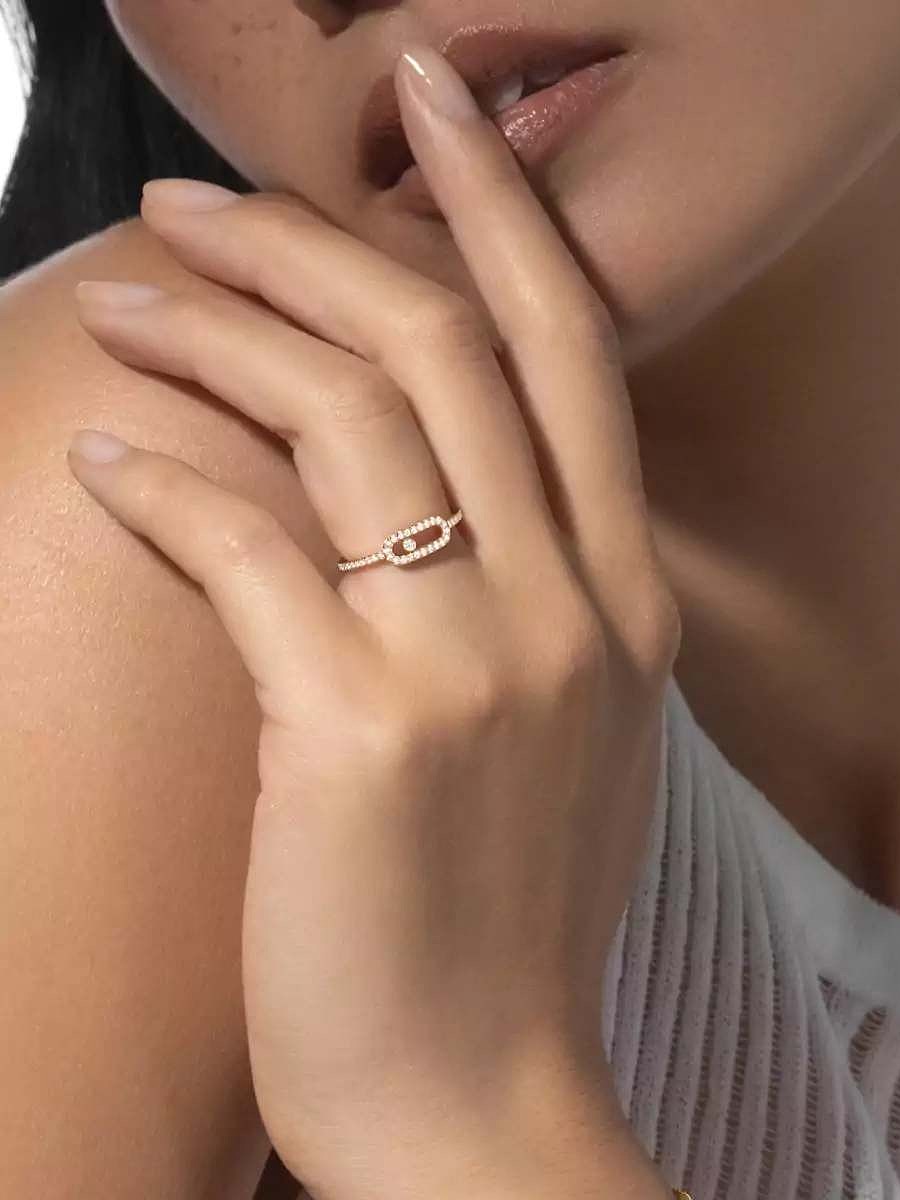 Gros plan sur la main d'une personne portant une délicate bague en or sertie de diamants ovales à l'annulaire.