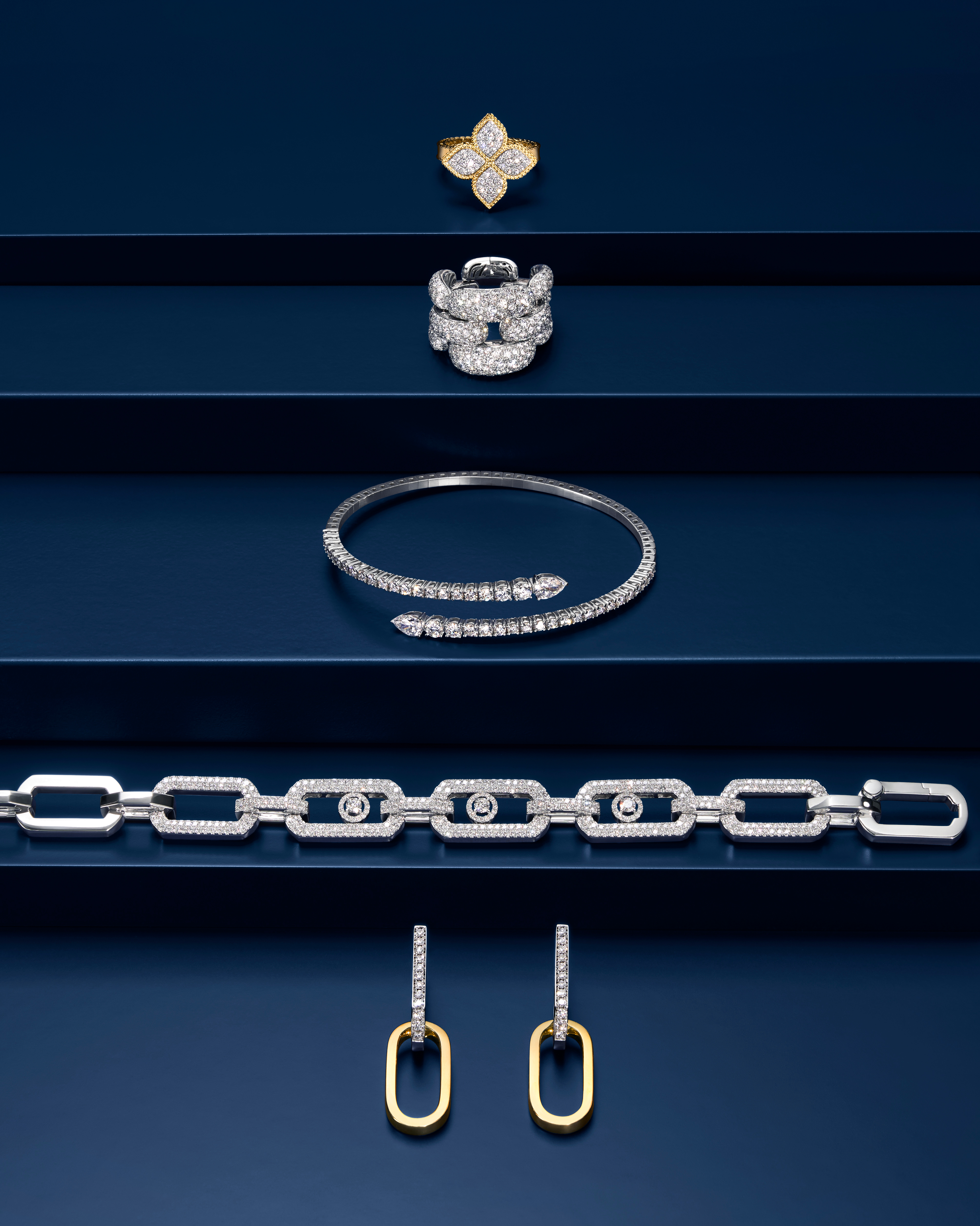 Eine Kollektion diamantbesetzter Gold- und Silberschmuckstücke, arrangiert auf fünf dunkelblauen Präsentationsetagen.