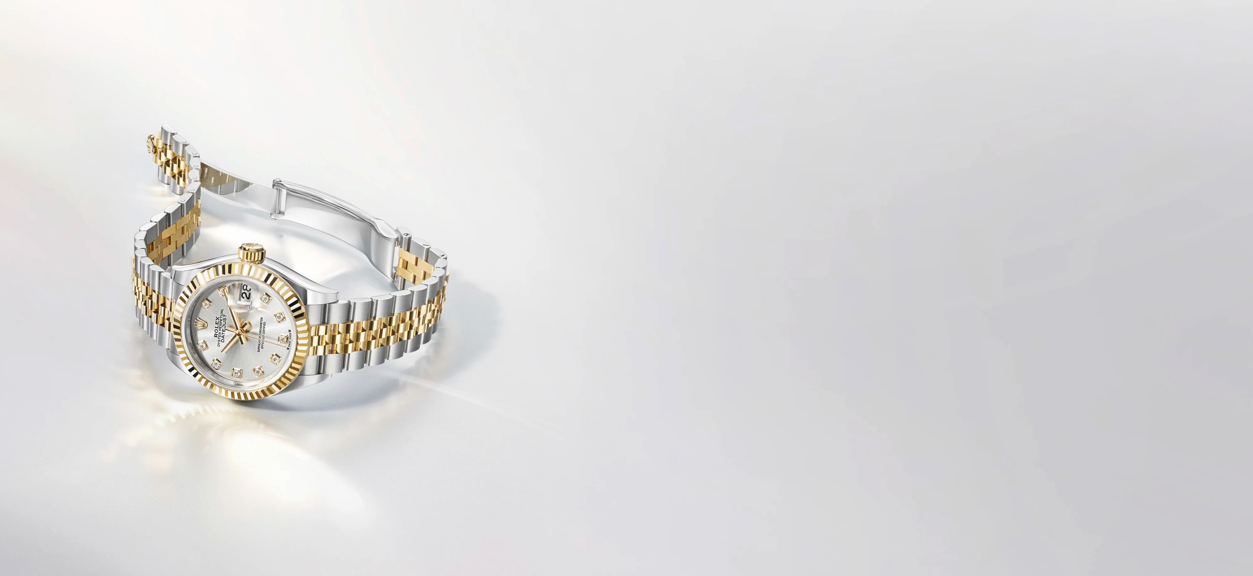 Une montre-bracelet Rolex bicolore, avec un cadran serti de diamants et un bracelet Jubilee, se détache sur un fond clair.