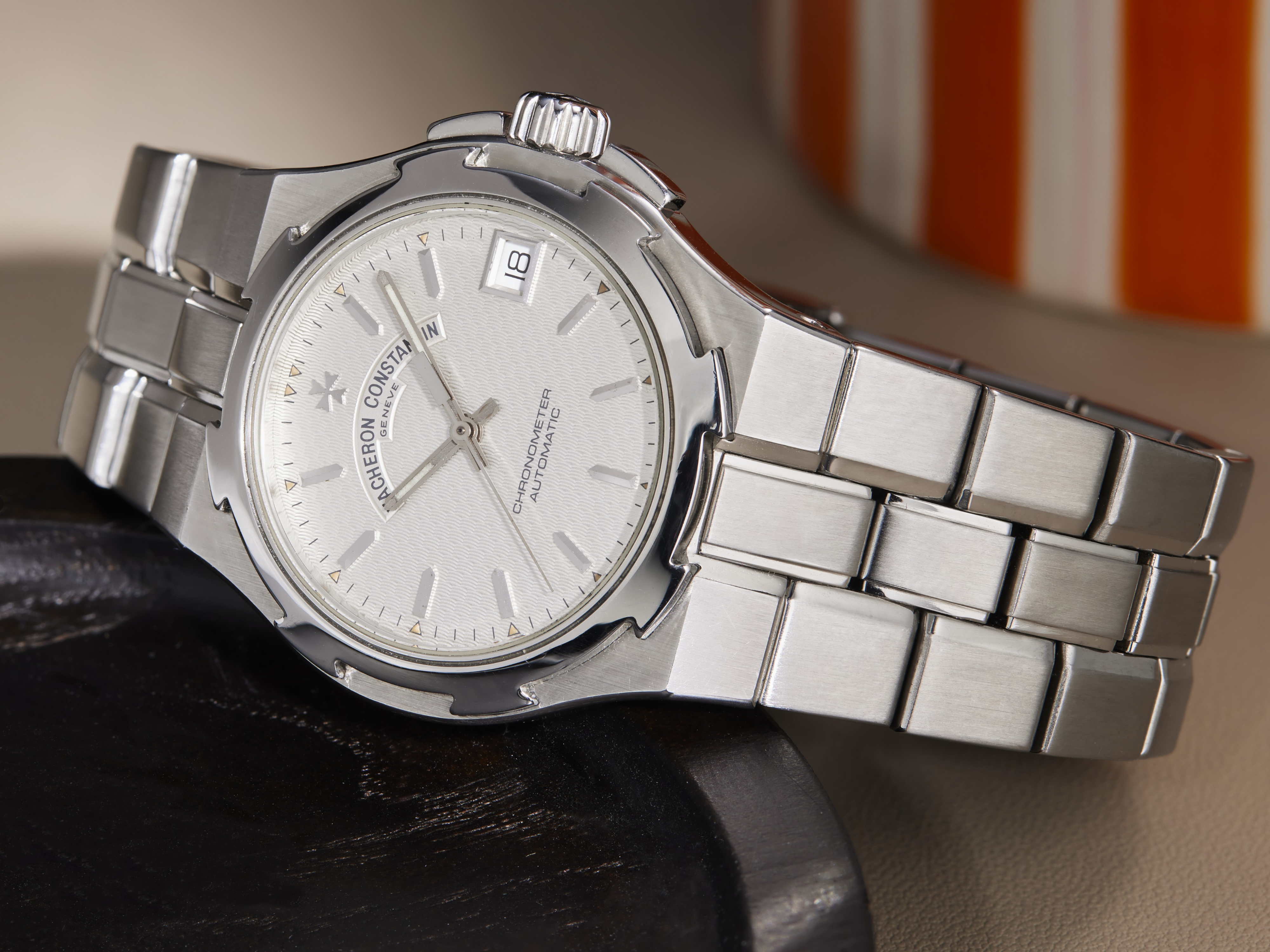 Eine Vacheron Constantin Armbanduhr mit silbernem Zifferblatt und Stahlarmband liegt auf einer dunklen Oberfläche.